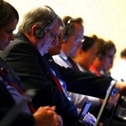 Učesnici konferencije sa slušalicama na glavi prate simultani prevod